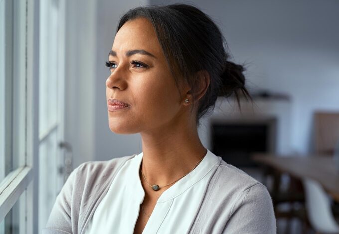 Woman looks out window and considers the mortgage pre-approval on her house.