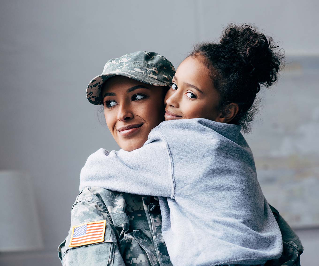 Mother in Military uniform hugs daughter inside hone purchased using VA loan.