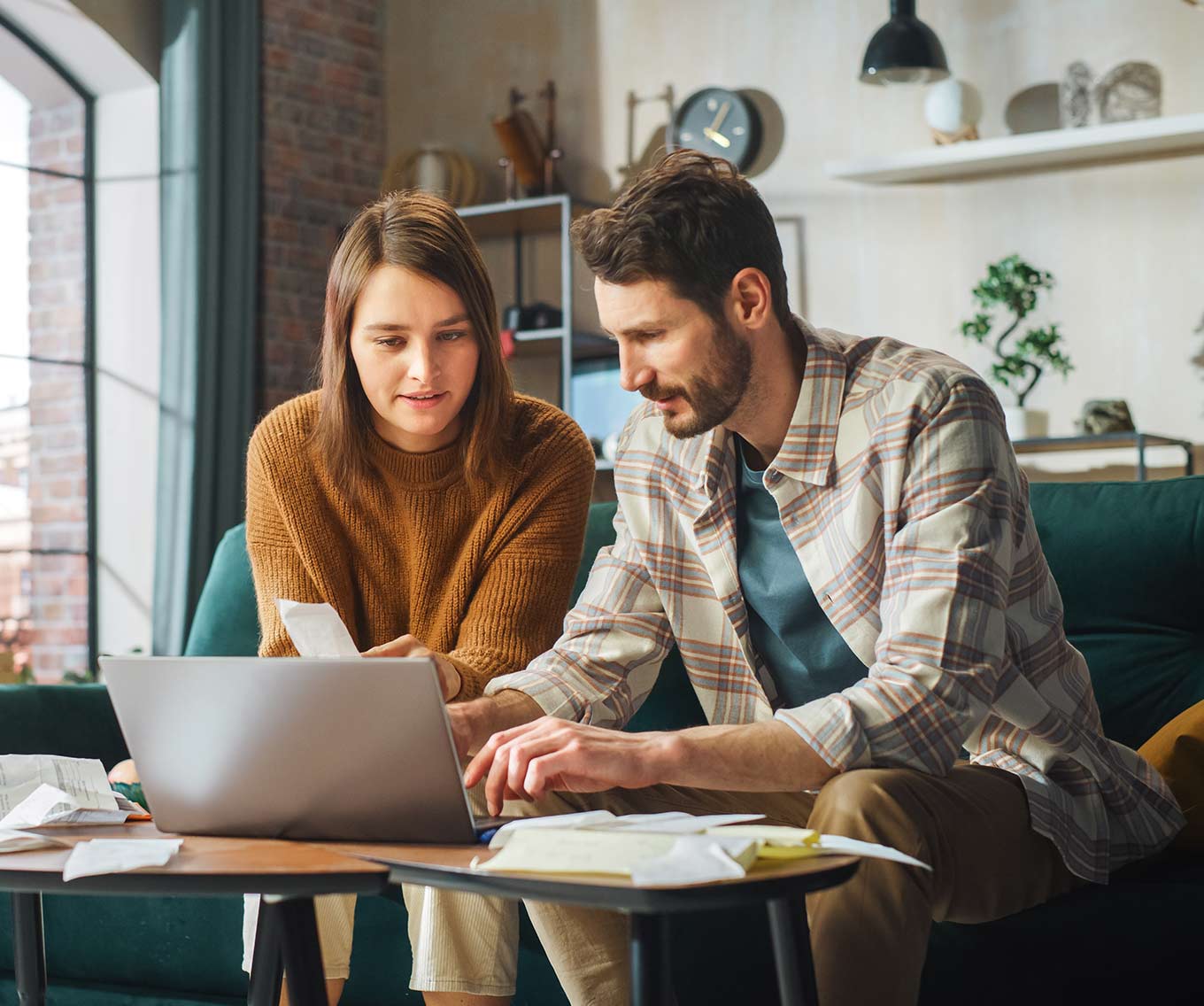 Couple sitting together on couch calculates what percent of their income should go to their mortgage.