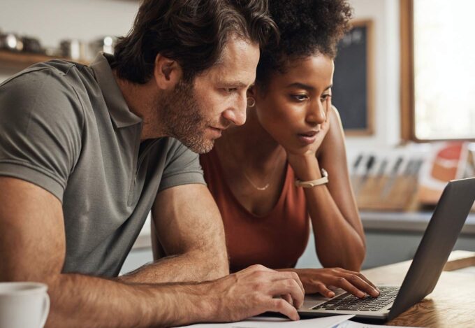 Couple researched renting out their primary residence together on a laptop.