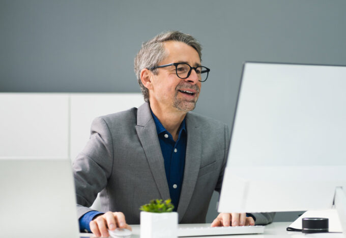 Man sitting at desk identifies a scam on his computer.
